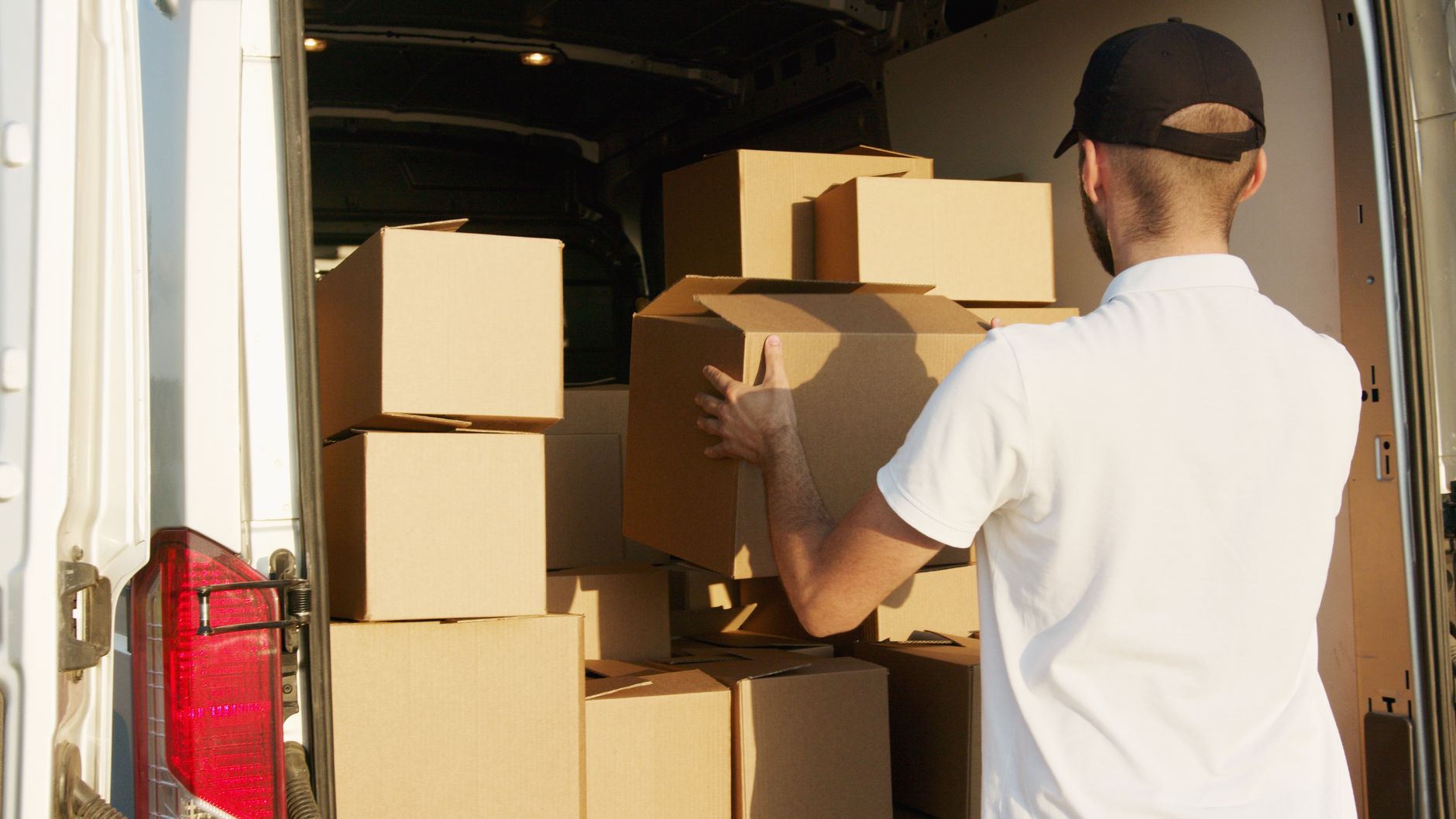 Person carrying a carton beside an open van